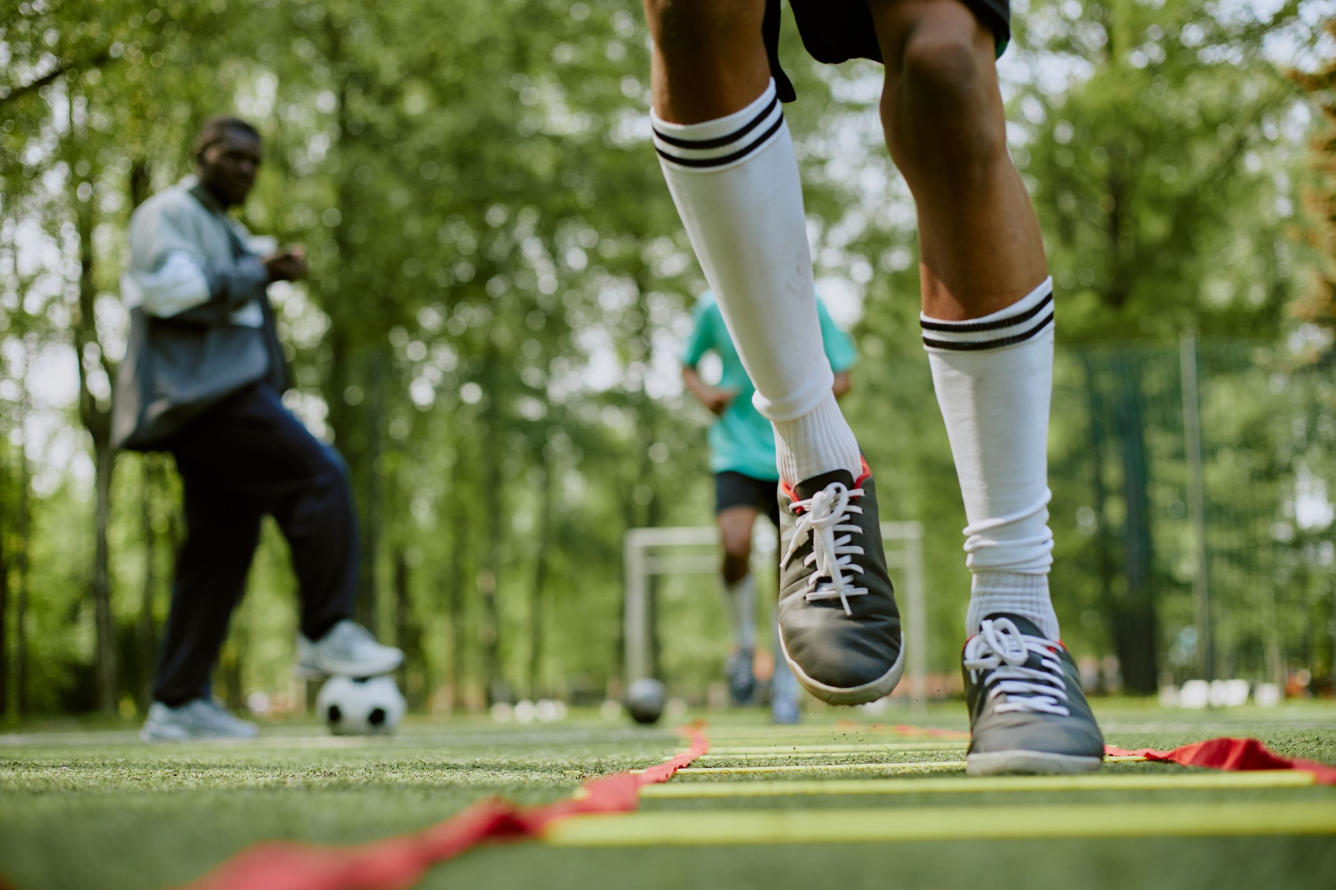 Teenage Boy Training Agility on Outdoor Field with Coach Observing