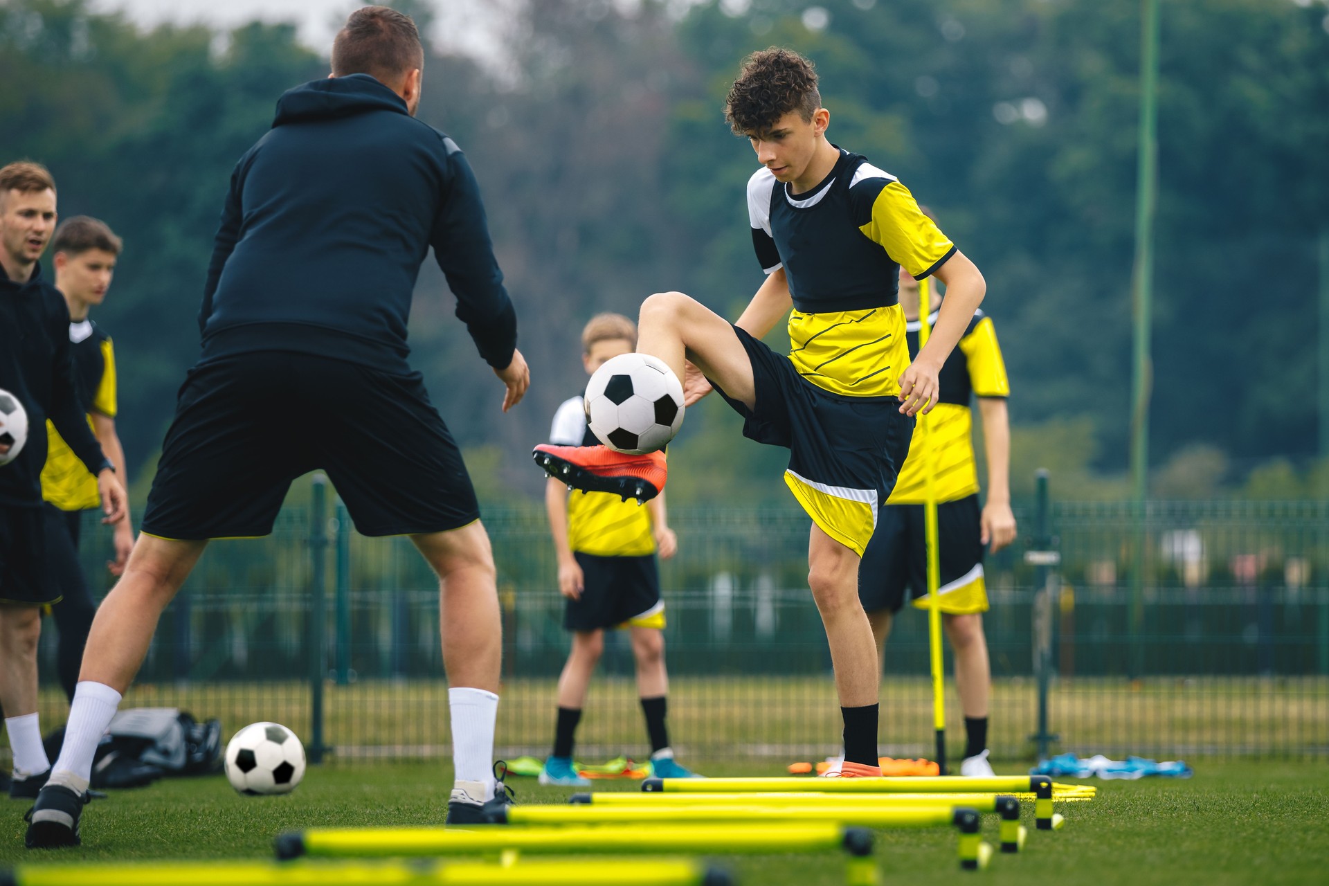 Soccer Boy on Training with Ball and Soccer Cones. Dribbling Drill. Soccer Kids Dribble Training. Youth Soccer Club Practice Session. Boys in Sports Team in Red Soccer Uniforms